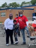 Staff standing in front of school food distribution with family