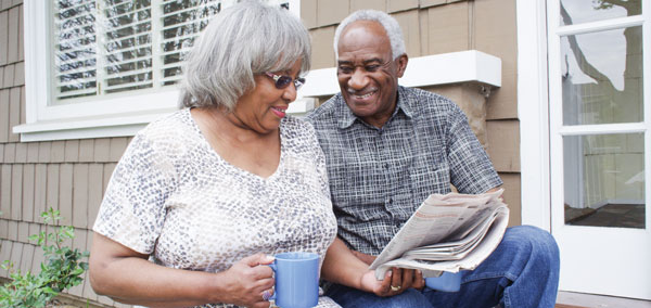 Elderly couple reading a newspaper while smiling