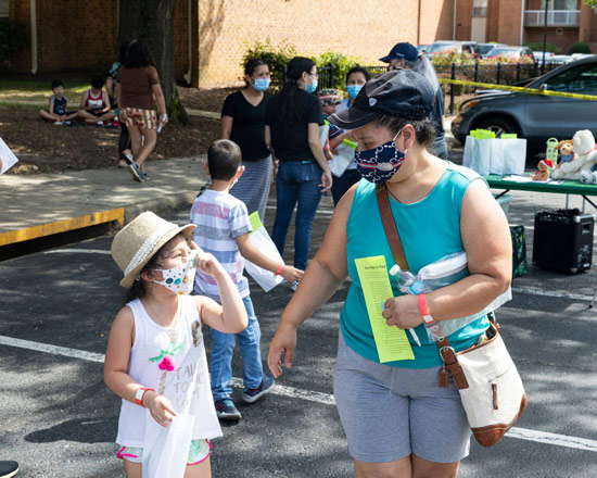 A mother and daughter walking at a community event with masks on