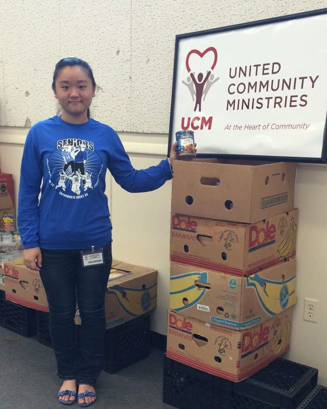 Young donor smiling next to old United Community Ministries sign