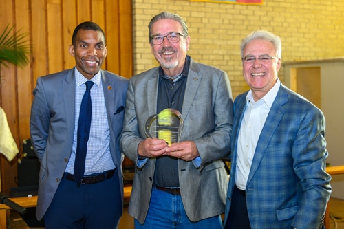 Rodney Lusk (left), Keary Kincannon (center), and Thomas Curcio (right), standing and smiling together as Kincannon holds the Gerry Hyland award