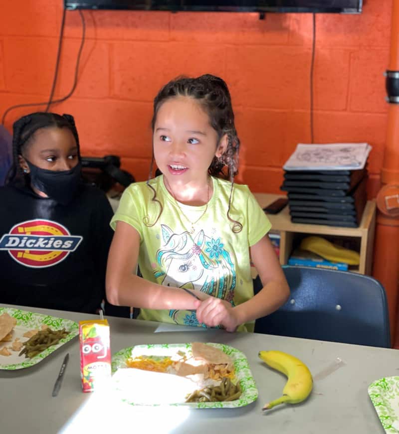 A young girl at Creekside Community Center enjoys a hot meal after school