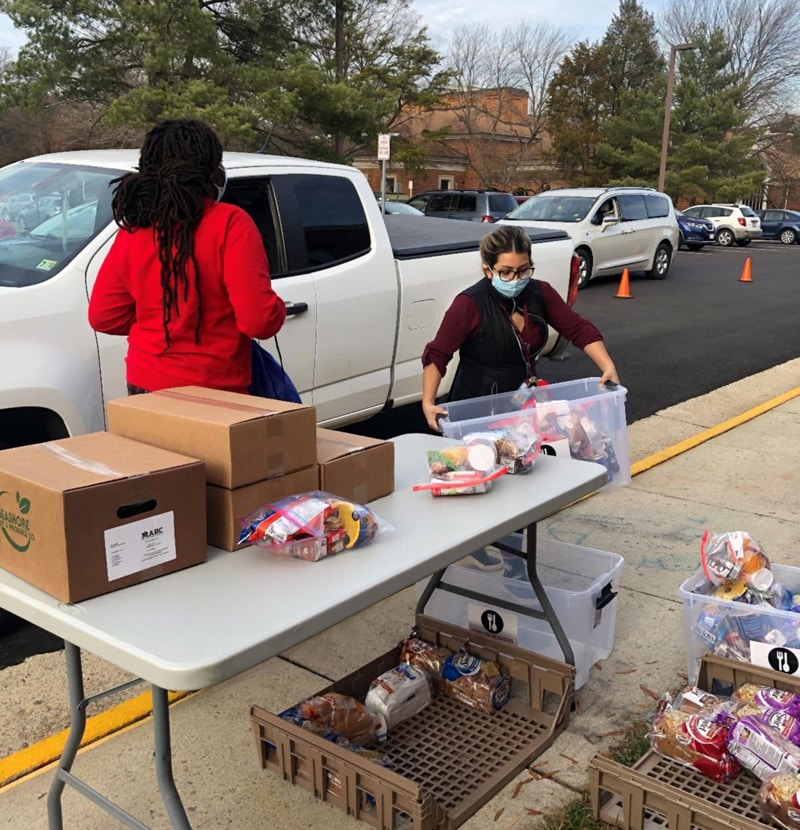 Delia, a community school coordinator, and a student load up a truck at family market day at Walt Whitman Middle School