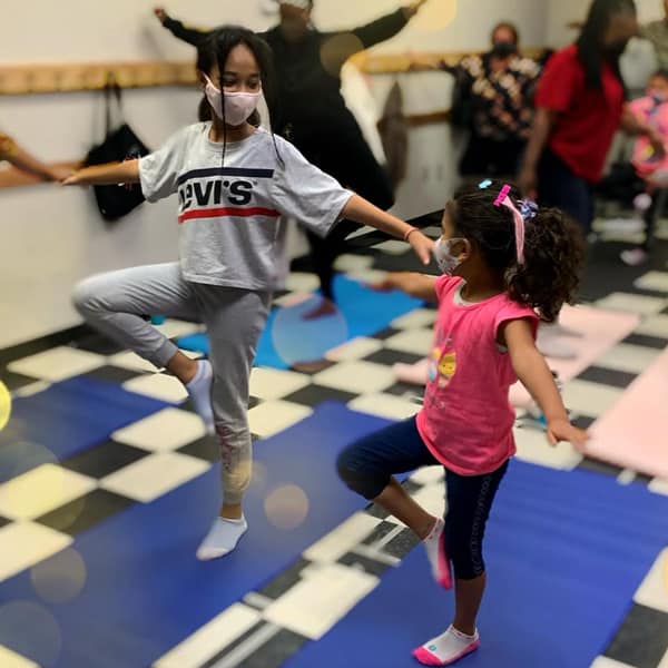 Two girls smile as they participate in Sacramento Neighborhood Center's Afrobeats Yoga and Movement class