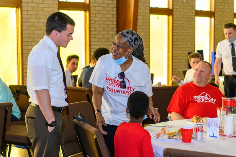 Smiling woman wearing a United Community Volunteer shirt talking to a young man