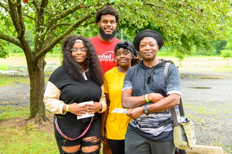 Rasheed Walker, 2022 Green Bay Packers draft pick, poses with 2 girls and a man at our Family Fun Day, hosted by the Family Achievement Program.