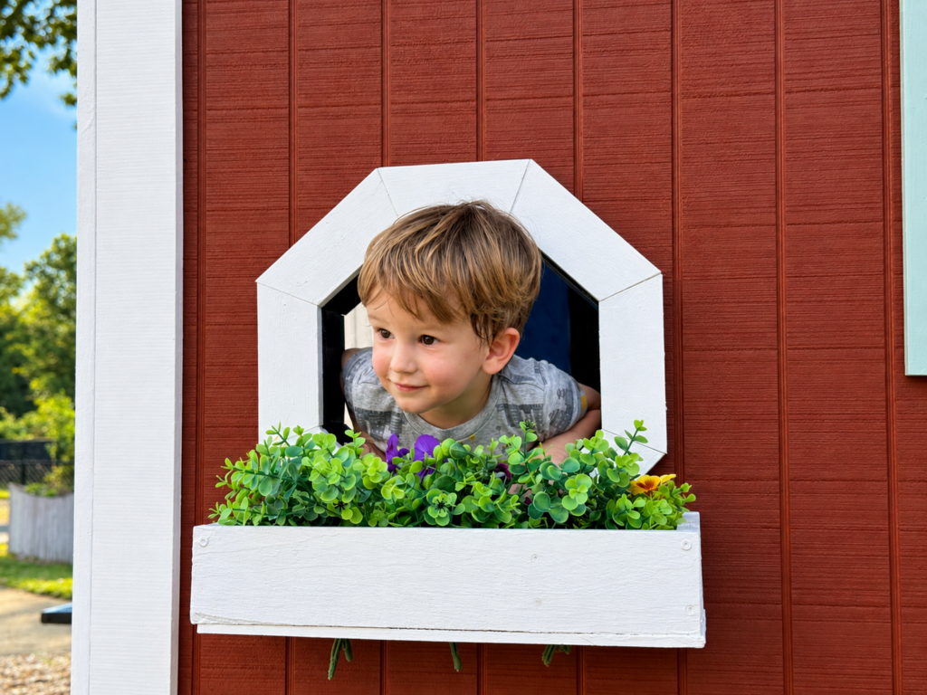 Little Boy in tiny house with flower boxes